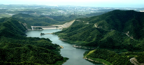 Image of a green river valley with a dam on one end.
