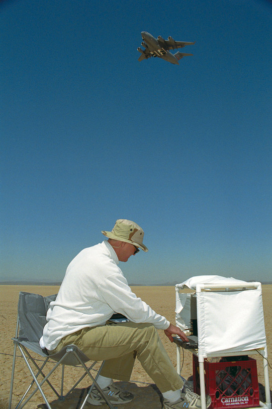 EDWARDS AIR FORCE BASE, Calif. -- Eric Kurth, an engineering student from California Polytechnic State University at San Luis Obispo, Calif., sits on Rogers Dry Lake Bed here Sept. 10 to record the noise footprint of the C-17 Globemaster III, flying above, as it attempted various landing approaches on Edwards. Mr. Kurth was participating in a noise mitigation study being conducted by NASA with an Edwards C-17. (U.S. Air Force photo by Tom Tschida)